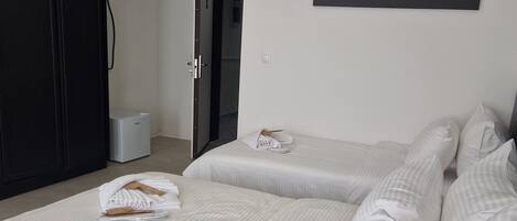 Une chambre d’hôtel avec deux lits, un tableau représentant un tigre accroché au mur et une armoire.