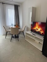 Una sala de estar moderna con chimenea, una mesa de comedor con sillas y un televisor sobre un mueble blanco.