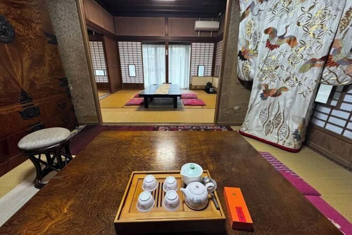 Una tradizionale stanza giapponese con pavimento in tatami, un tavolino con un set da tè e una porta scorrevole decorata con un motivo floreale.