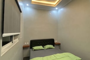 Un dormitorio con cama, ventana y lámpara en el techo.
