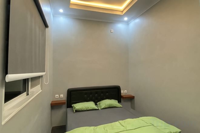 Un dormitorio con cama, ventana y lámpara en el techo.