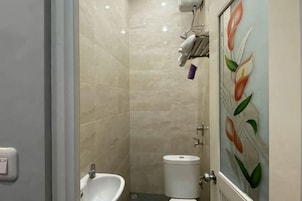 Un baño con inodoro, bidé y un perchero de toallas en la pared.