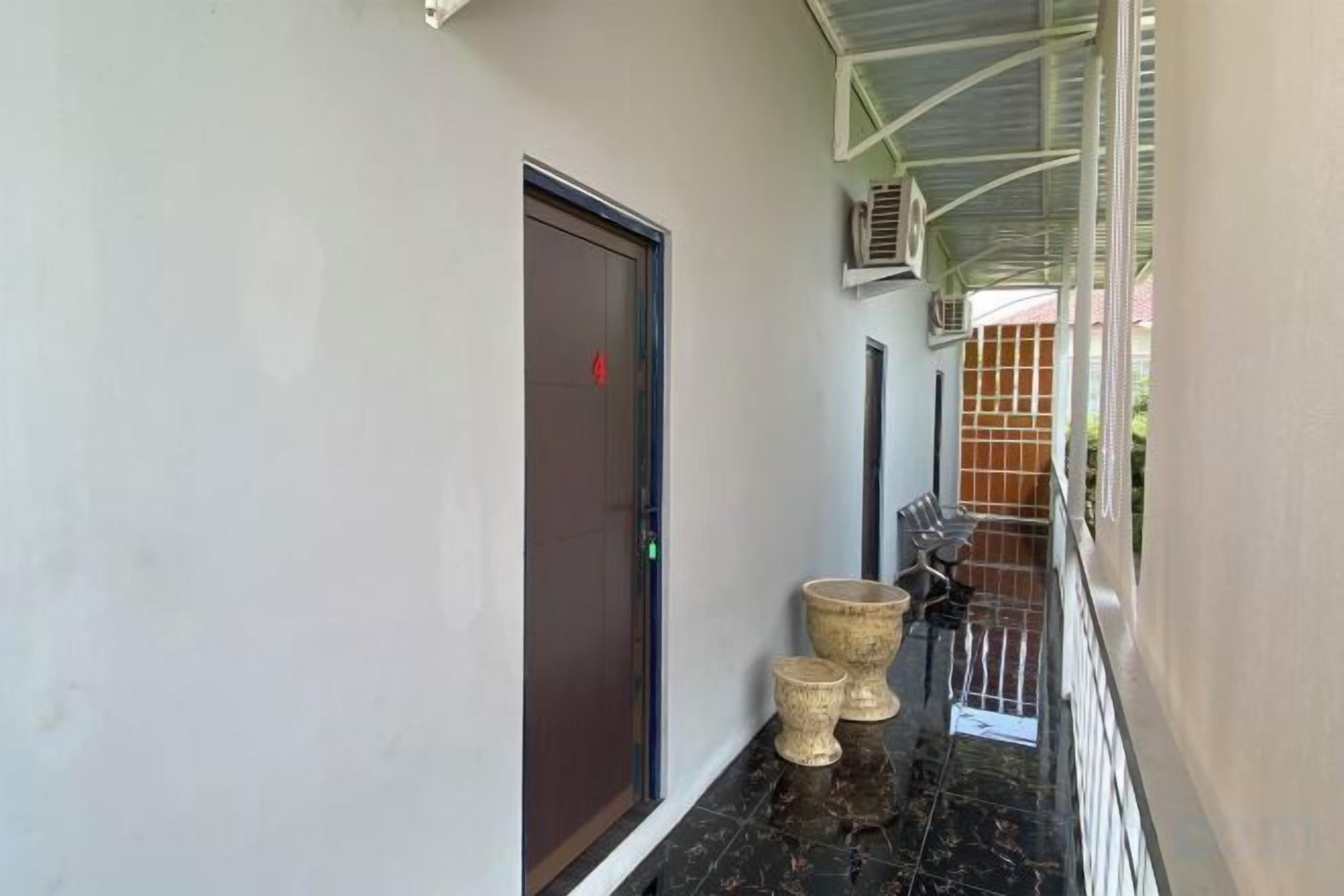 A corridor with a door, a trash bin, and a railing.