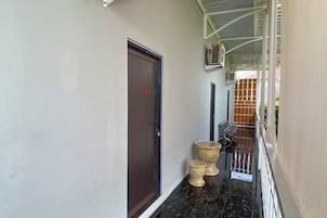 Un pasillo con una puerta, un bote de basura y una barandilla.