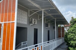 A building with a covered balcony, air conditioning units, and a white railing.