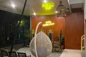 A reception area with a wooden wall, a hanging light fixture, and a sign that reads 'Riffa Homestay'. - Homestay Riffa Syariah (Prambanan)