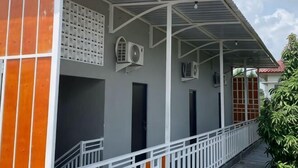 Un bâtiment doté d’un porche couvert, de climatiseurs et d’une balustrade blanche.