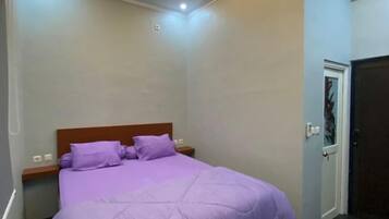 A bedroom with a bed, a nightstand, a door, and a ceiling light.
