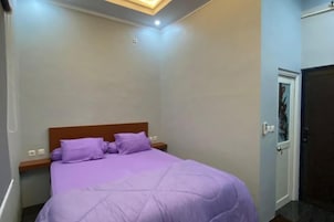Un dormitorio con cama, mesita de noche, puerta y lámpara en el techo.