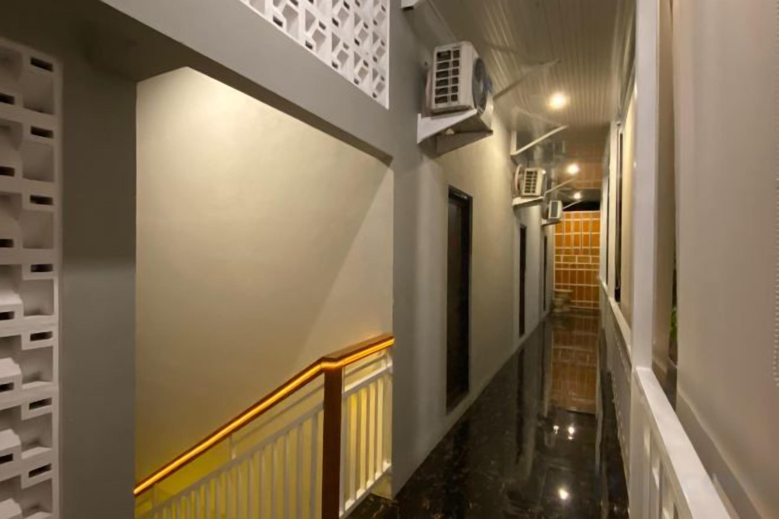 Um corredor com piso de mármore, corrimão branco e unidades de ar condicionado na parede.