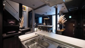 A modern kitchen with a built-in dishwasher, a sink with a dish rack, and a dining area with a bar. - Trive Ozone (Nagoya)