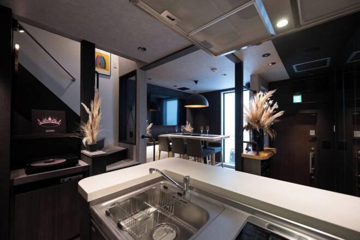A modern kitchen with a built-in dishwasher, a sink with a dish rack, and a dining area with a bar.