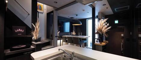 A modern kitchen with a built-in dishwasher, a sink with a dish rack, and a dining area with a bar.