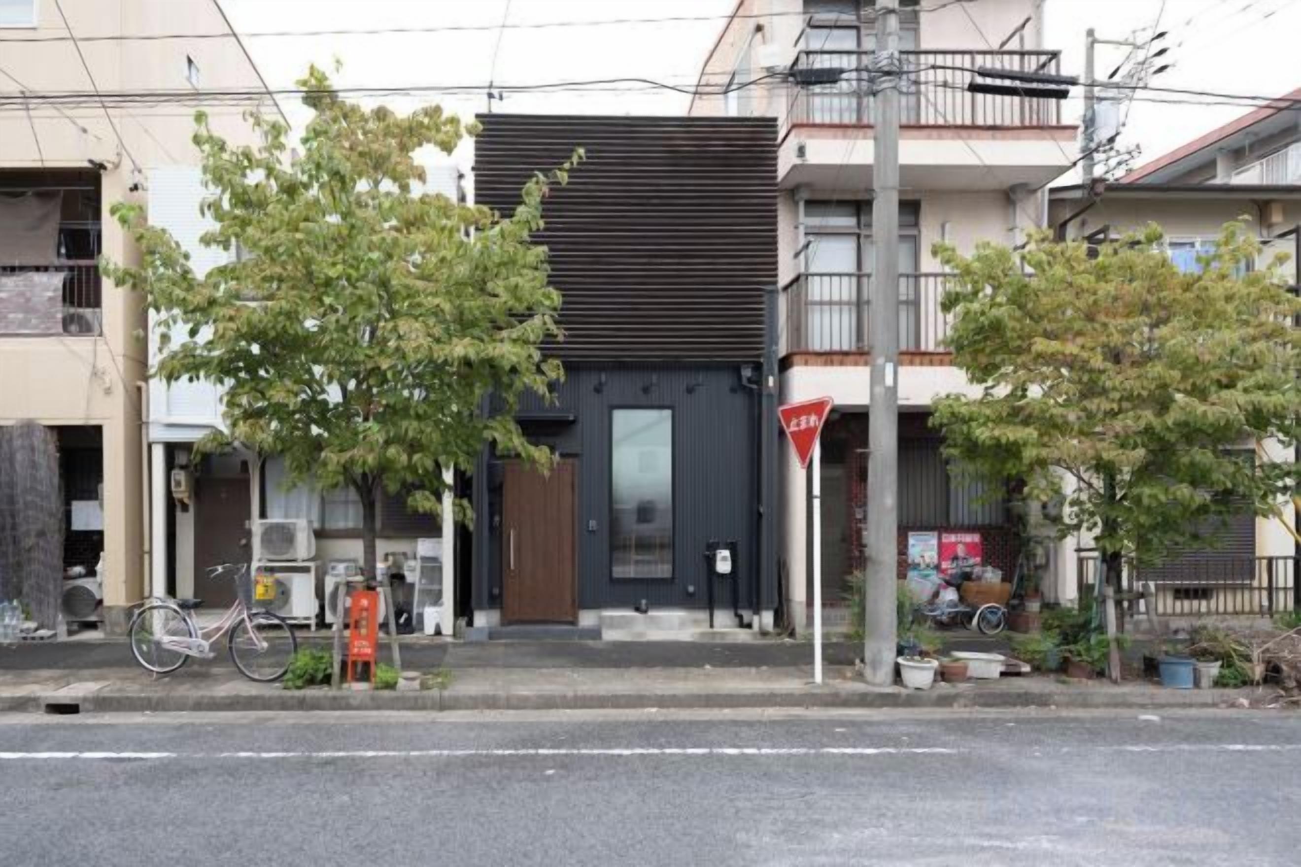 A building with a modern facade, a bicycle parked outside, and a tree in front.