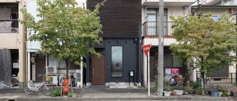 A building with a modern facade, a bicycle parked outside, and a tree in front.