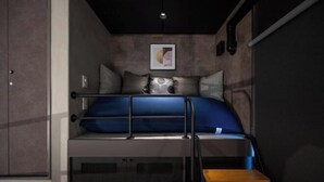 A bunk bed with a ladder, a framed picture on the wall, and a small wooden table. - Trive Ozone (Nagoya)