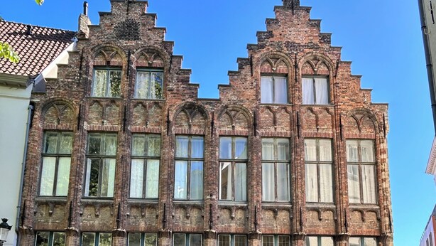 Een historisch gebouw met een symmetrische gevel, grote ramen en een houten deur in het midden.