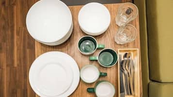 A neatly arranged table with plates, cups, and cutlery on a wooden tray.