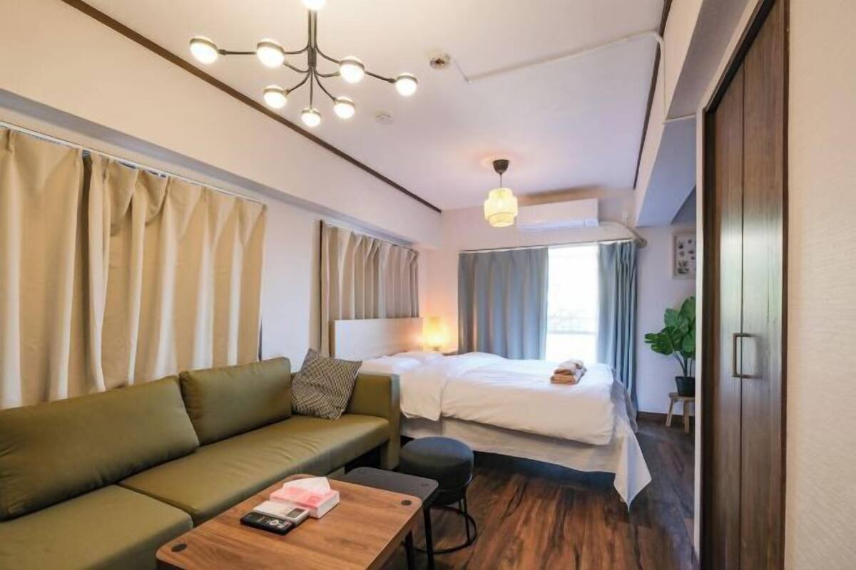 Una habitación de hotel moderna con sofá, cama, una mesita y una lámpara en el techo.