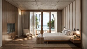 A modern bedroom with a large bed, a TV, a seating area with a view of the ocean, and a wooden floor. - Nyne Hotels Anugrah - Bentota (Bentota)