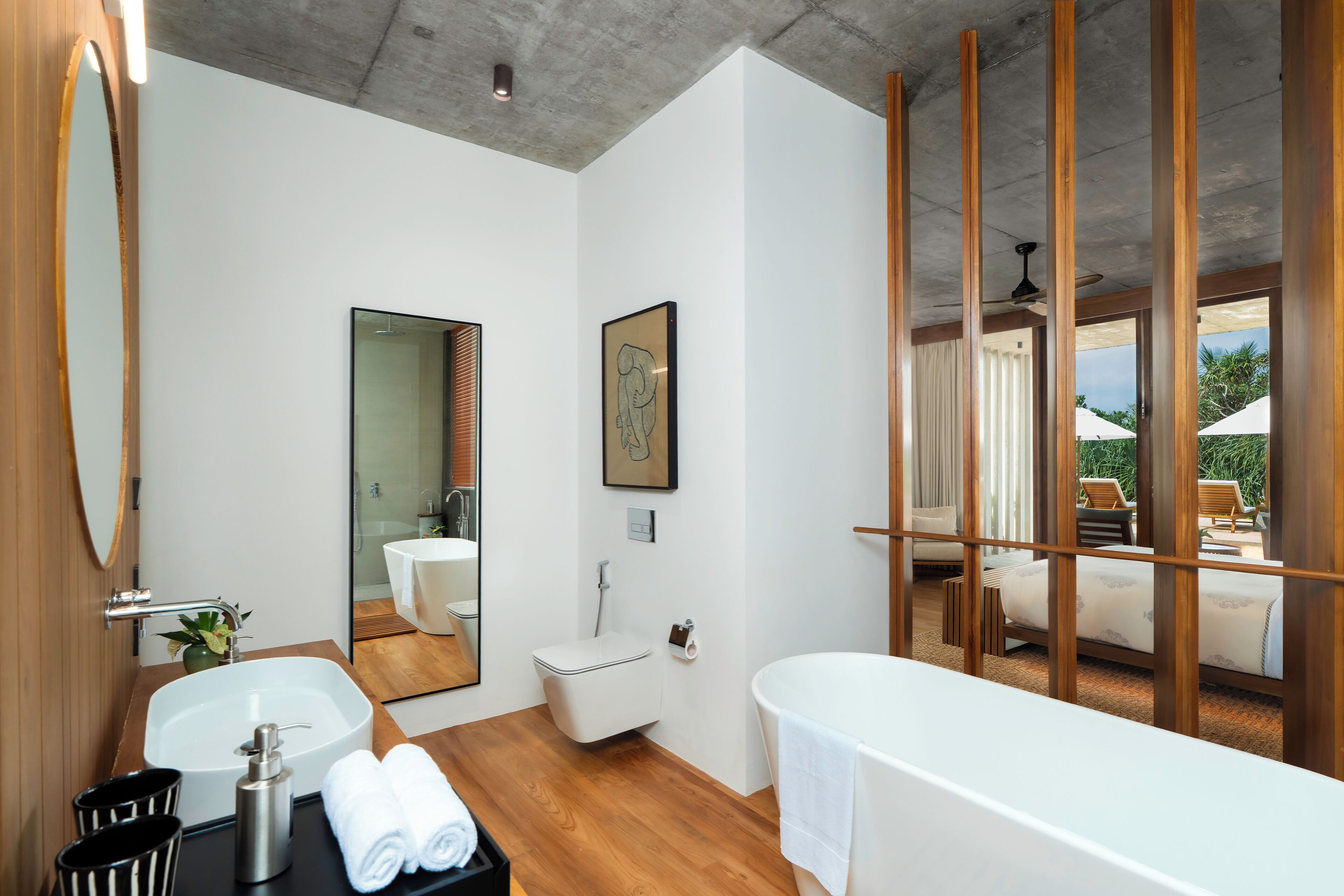 A modern bathroom with a large mirror, a bathtub, a sink, and a toilet.