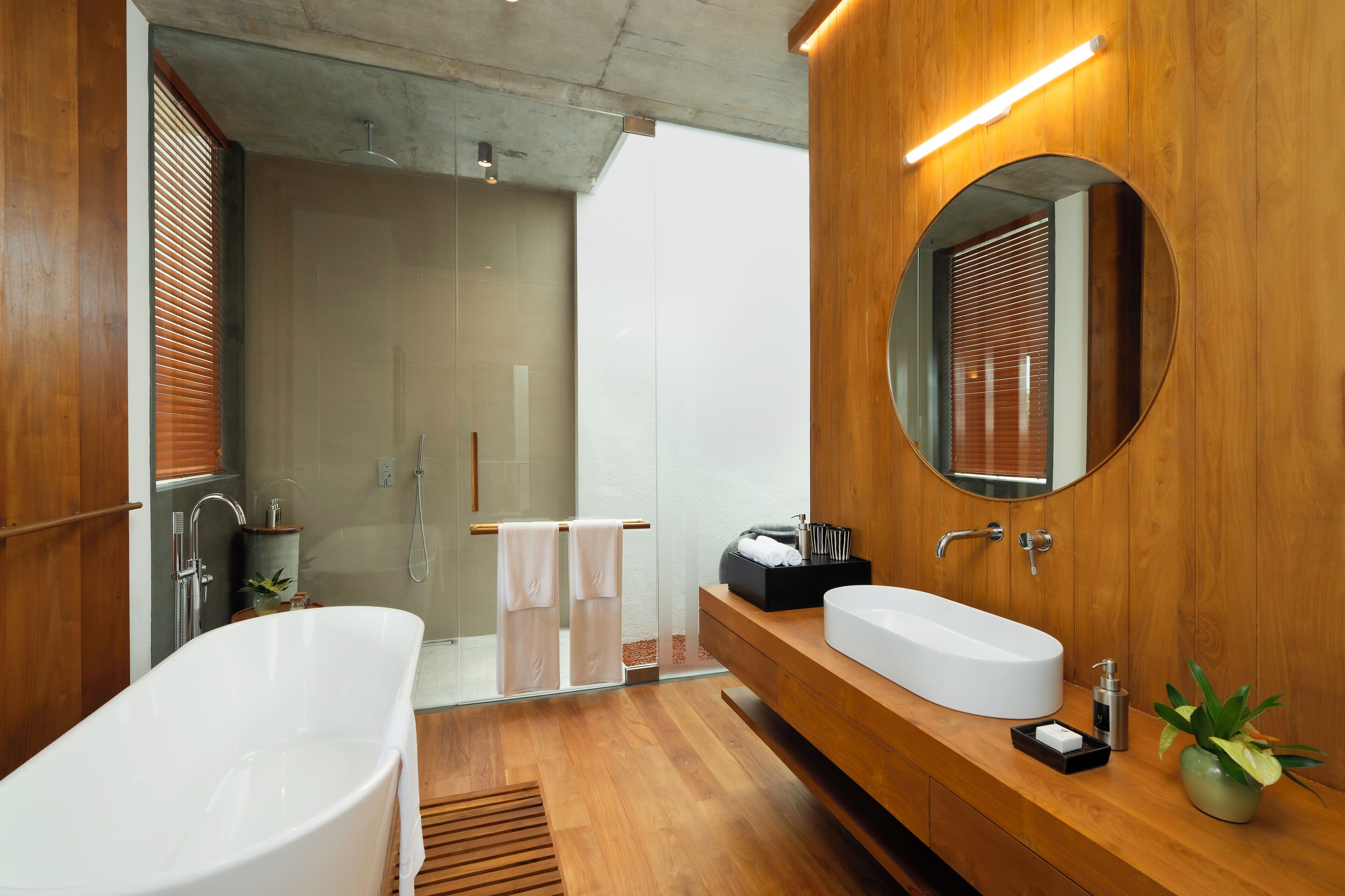 A modern bathroom with a freestanding bathtub, a large mirror, and a wooden vanity.