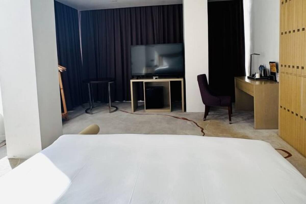 Une chambre d’hôtel comprenant un lit, un bureau, une chaise, une télévision et une armoire.