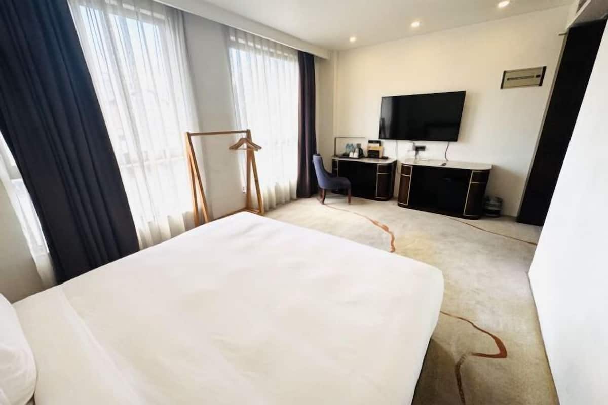 Une chambre d’hôtel équipée d’un lit, d’un bureau, d’une chaise, d’une télévision et d’un porte-manteau.