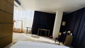 A hotel room with a large bed, a desk, a chair, and a TV. - Huadu Hotel (Kathmandu)