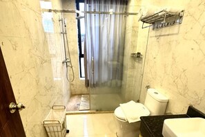 A bathroom with a glass-enclosed shower, a toilet, and a sink. - Huadu Hotel (Kathmandu)