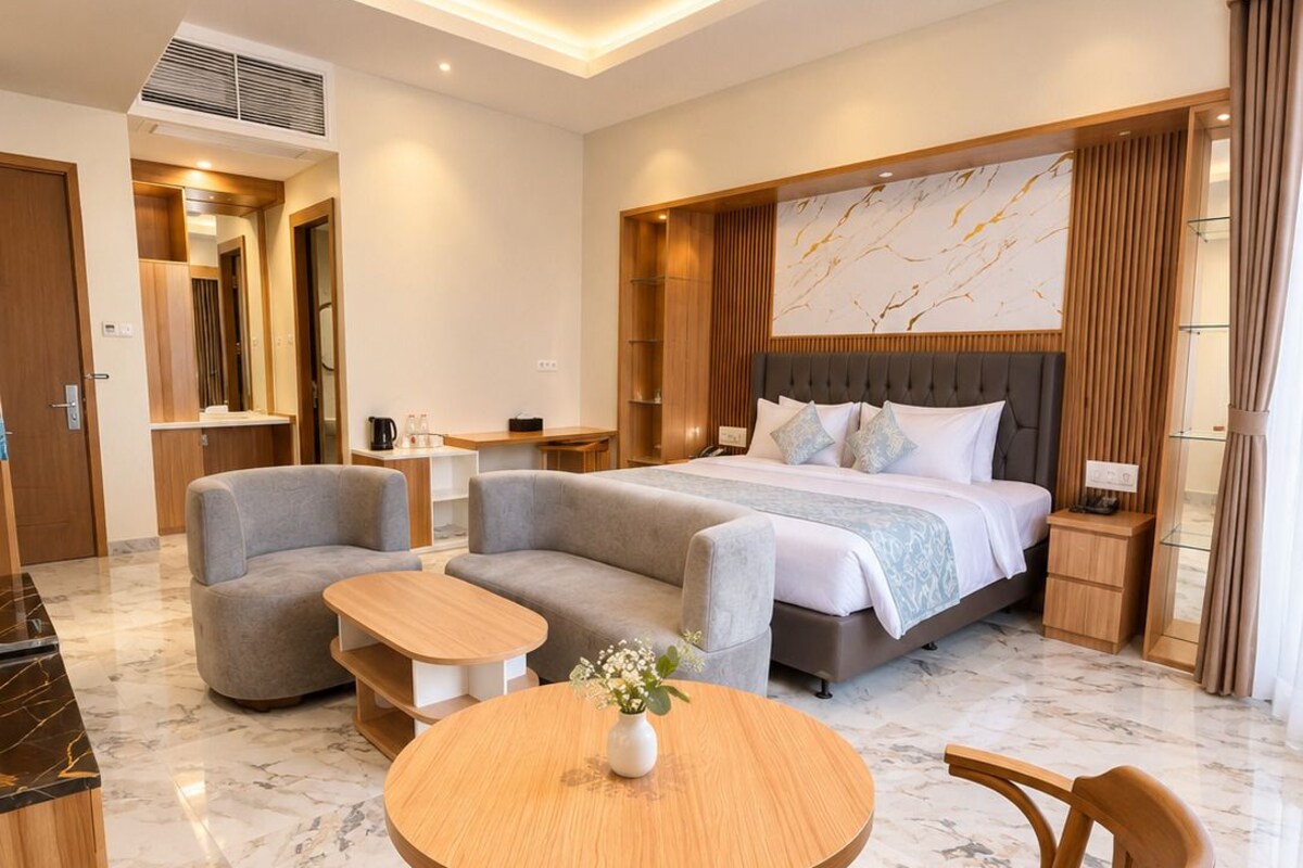 A modern hotel room with a bed, sofa, dining table, and chairs.