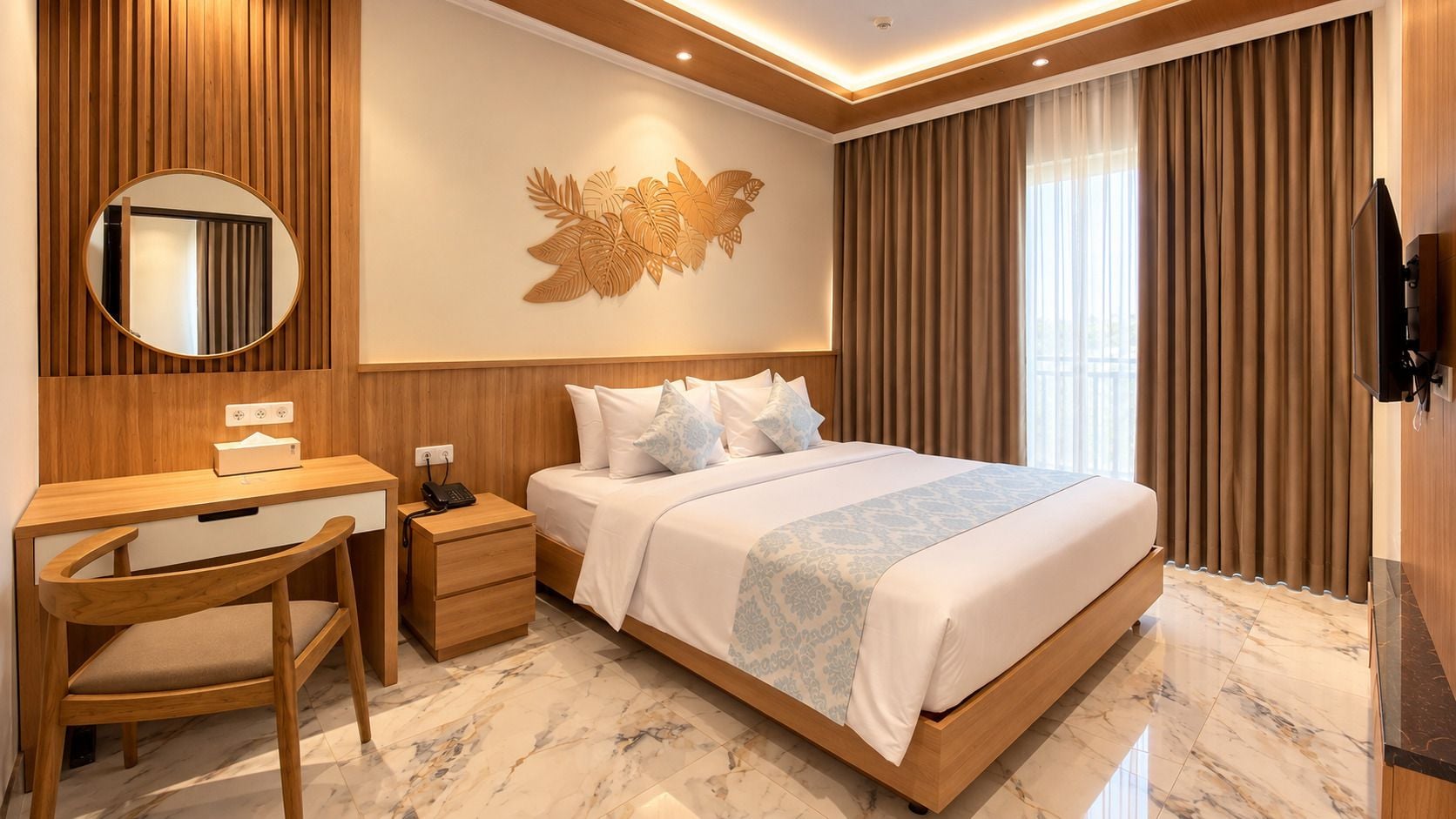 Habitación de hotel con cama, escritorio, silla y televisor instalado en la pared.