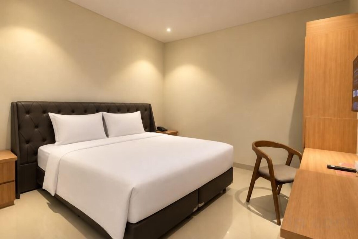 A bedroom with a large bed, bedside tables, a wooden wardrobe, and a chair.