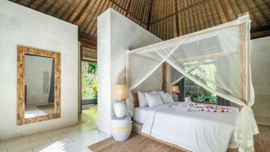 A bedroom with a bed, bedside table, lamp, and a canopy bed. - VillaJewel Bali (Bali)
