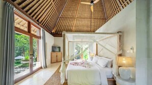 A bedroom with a canopy bed, large windows, and a view of greenery. - VillaJewel Bali (Bali)