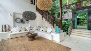 A modern interior with a white sofa, a wooden coffee table, and a staircase leading to an outdoor area. - VillaJewel Bali (Bali)
