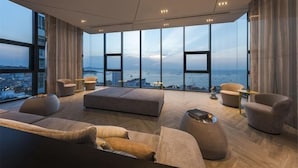 A modern living room with a panoramic city view, large windows, and contemporary furniture. - Pattaya Base Seascape Apartment (Pattaya)