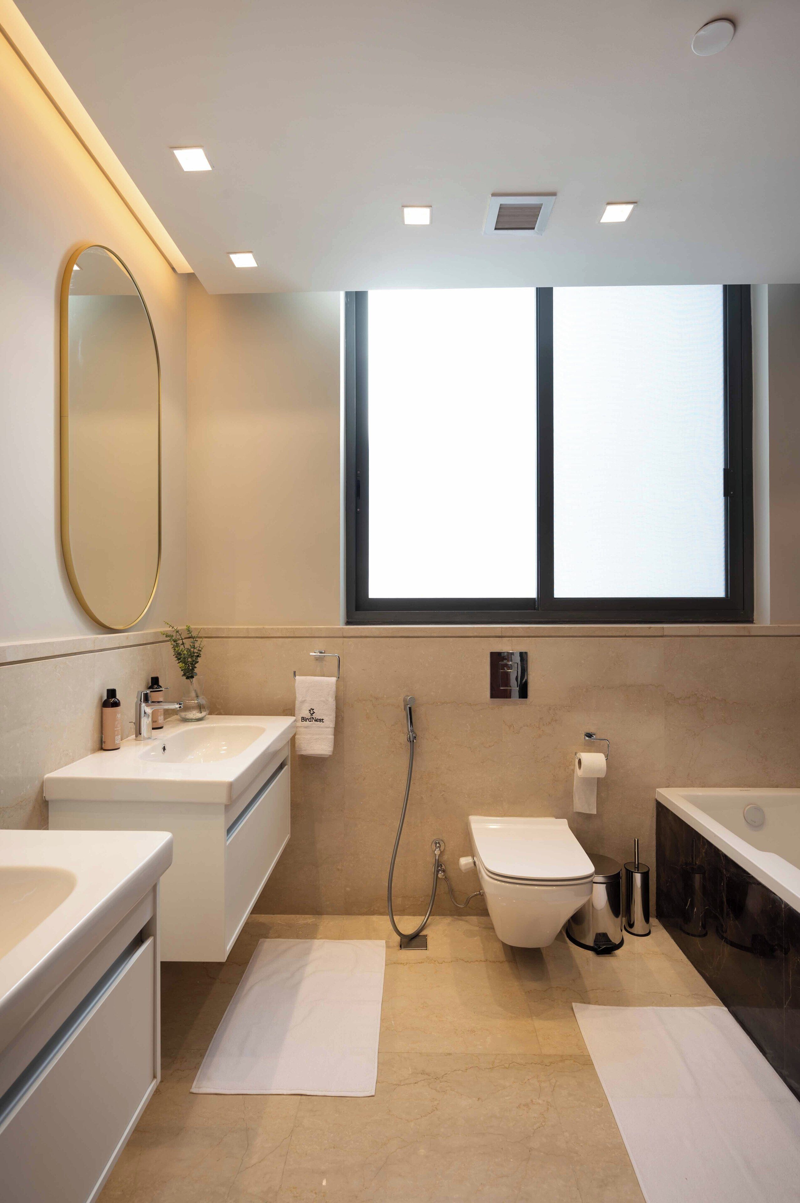 A modern bathroom with a large mirror, a toilet, a bidet, and a bathtub.
