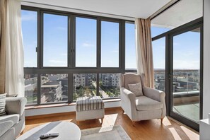 Un salon moderne avec une grande fenêtre, un canapé, une table basse et une télécommande posée sur la table.