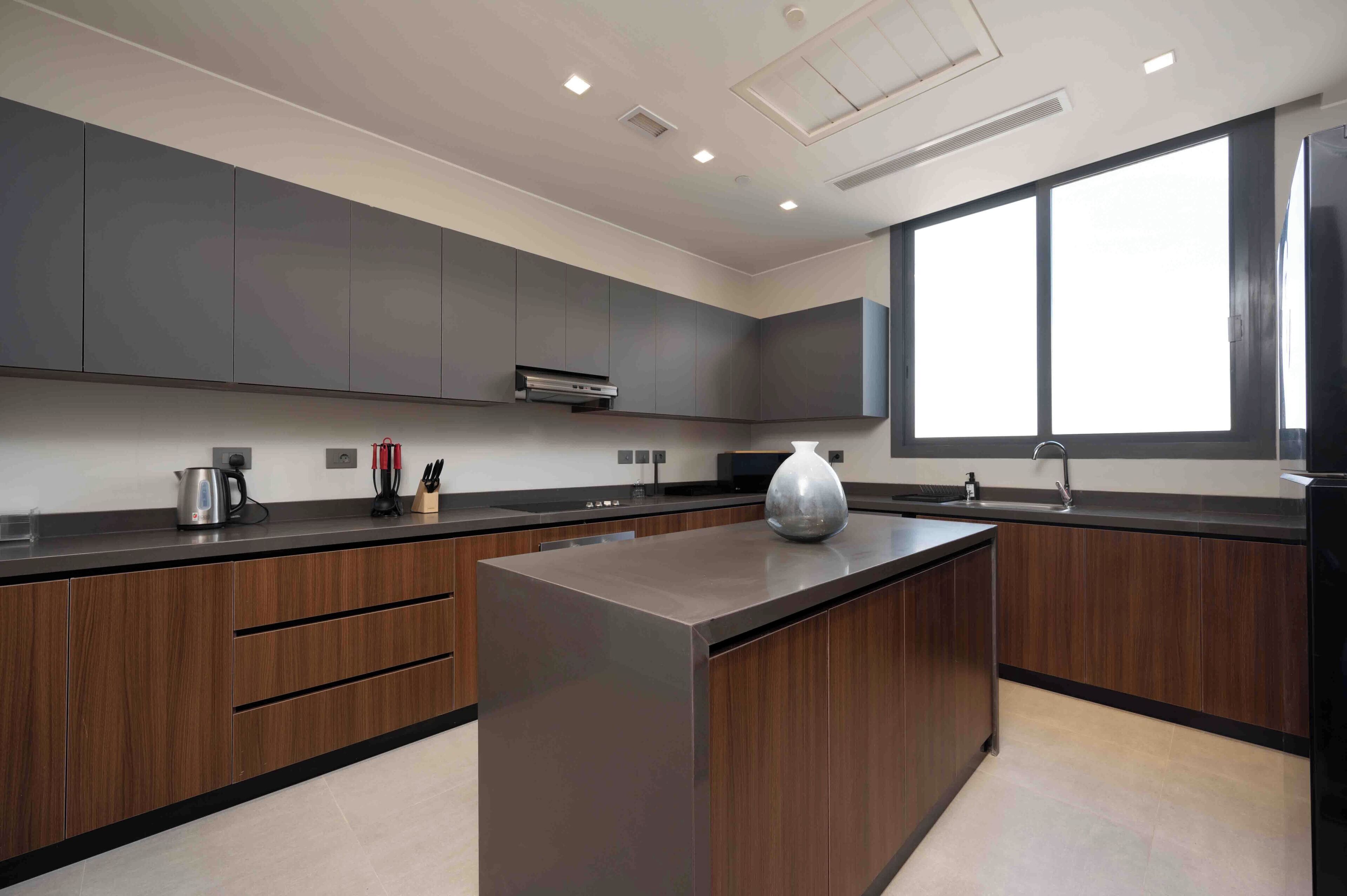 A modern kitchen with dark wood cabinets, a central island, and a large window providing natural light.