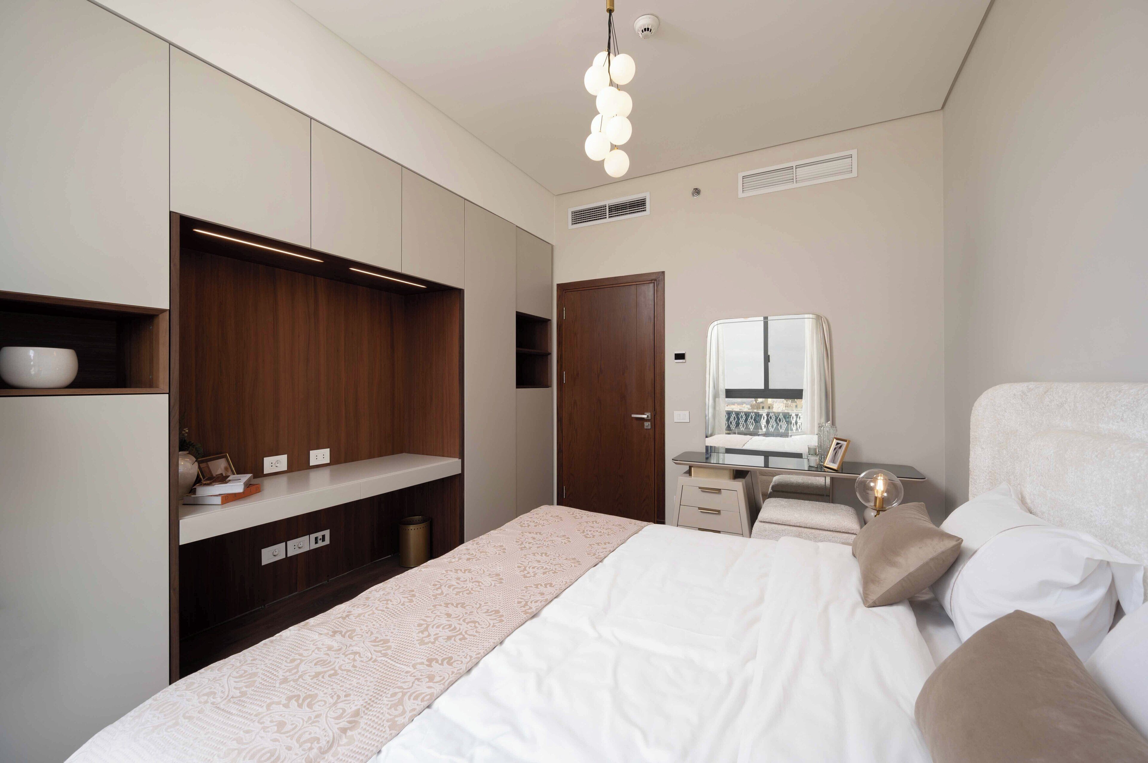 Une chambre moderne avec un grand lit, une armoire intégrée, une table de chevet et un miroir.