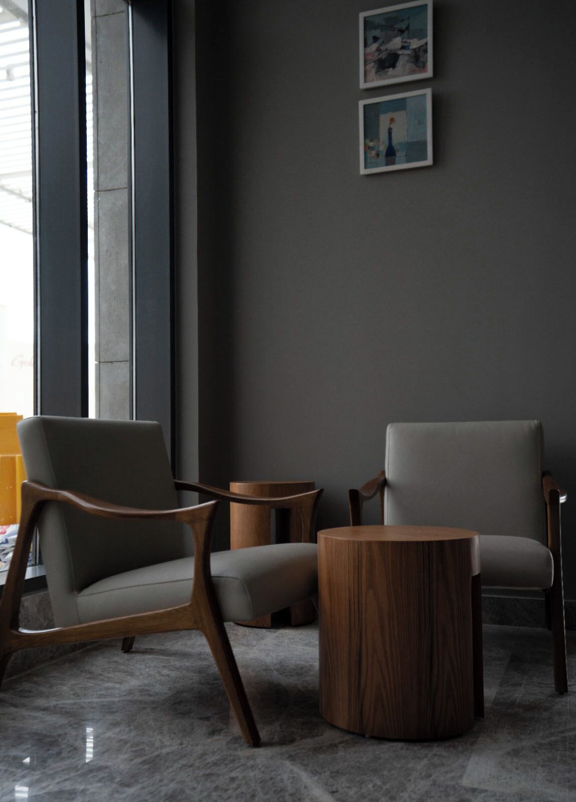 Ein modernes Zimmer mit zwei grauen Sesseln, einem hölzernen Beistelltisch und einem runden Couchtisch.