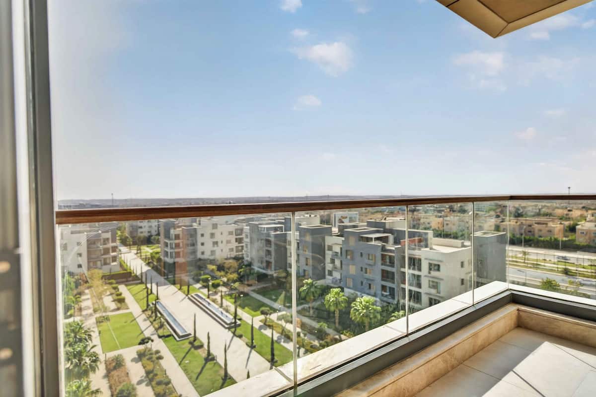 A modern apartment with a balcony, large windows, and a view of a residential area.