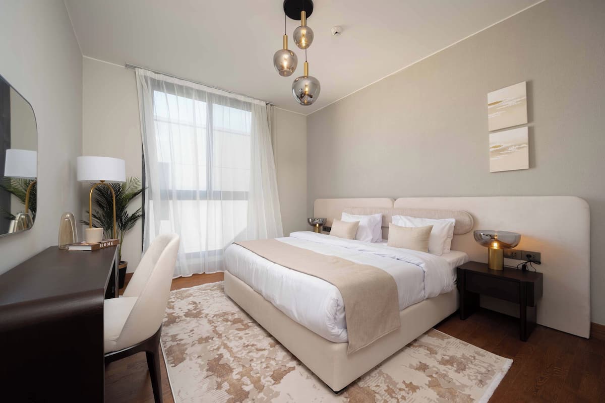 A modern bedroom with a large bed, bedside tables, a desk, and a chair.