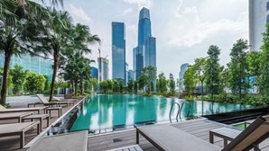 Un espace aménagé au bord de la piscine, avec des chaises longues et une vue sur les gratte-ciel modernes qui se dressent à l’arrière-plan.