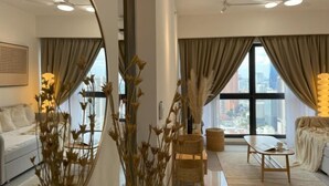 Un salon moderne avec un canapé, une table basse et une vue sur la ville grâce à de grandes fenêtres.