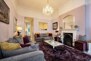 A living room with a fireplace, two sofas, a coffee table, and a chandelier. - The Brook Green Retreat (London)