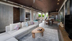 A modern living area with a sofa, coffee table, ceiling fan, and large windows. - D'Padi Villa Canggu (Bali)