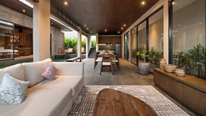 A modern interior with a sofa, dining table, and potted plants. - D'Padi Villa Canggu (Bali)