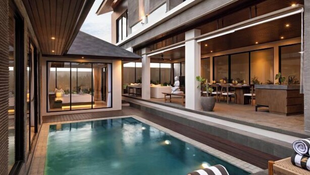 A modern pool area with a glass-enclosed lounge, a dining area with outdoor seating, and a bar. - D'Padi Villa Canggu (Bali)